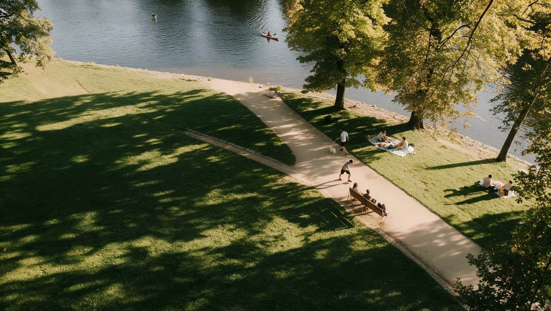 People walking and picnicking beside a river, seen from above